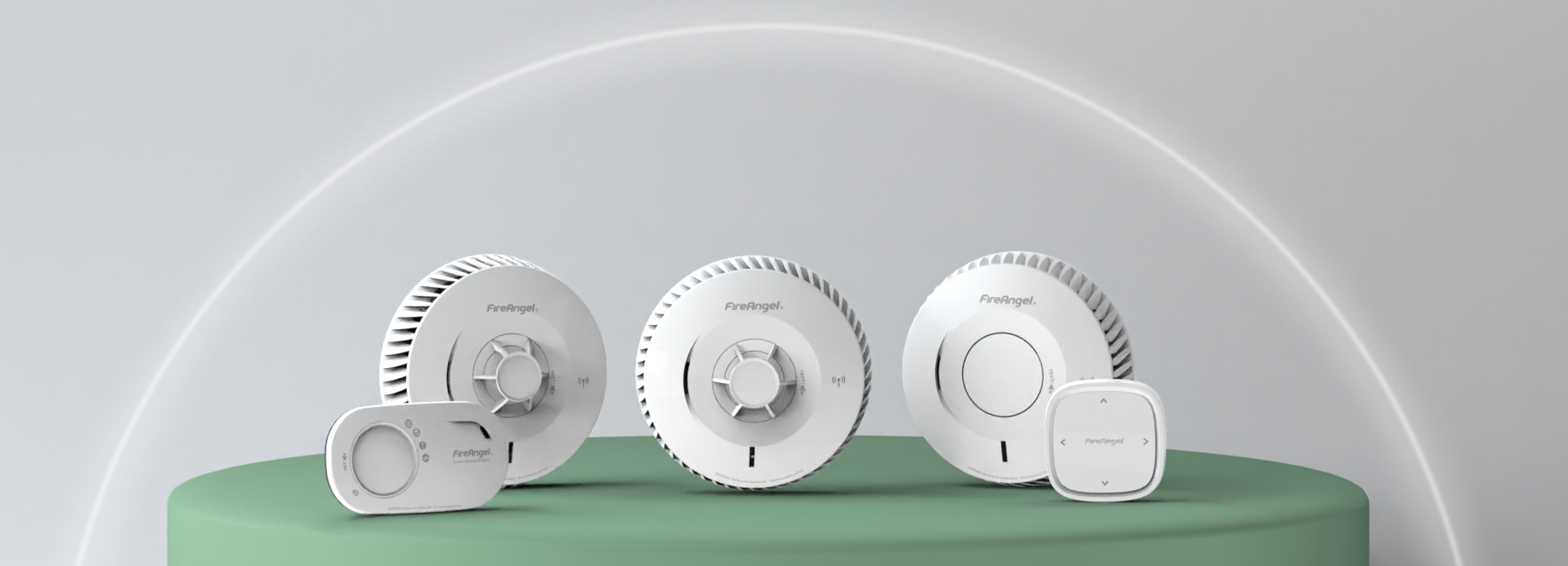 Four white linked alarms sit on a green surface with a light grey background.