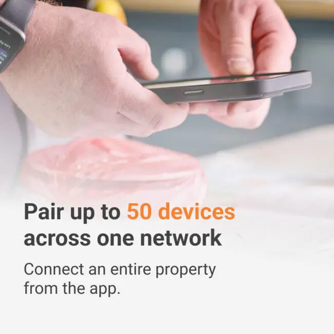 Hands holding an Angel Pro mobile showing text about pairing 50 devices on one network.