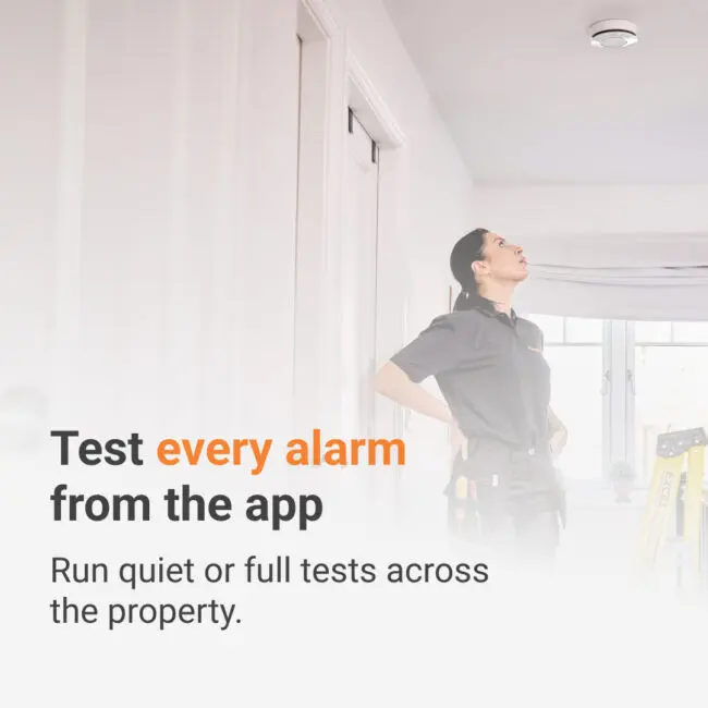 A technician looking up at a ceiling-mounted Angel Pro App smoke alarm.